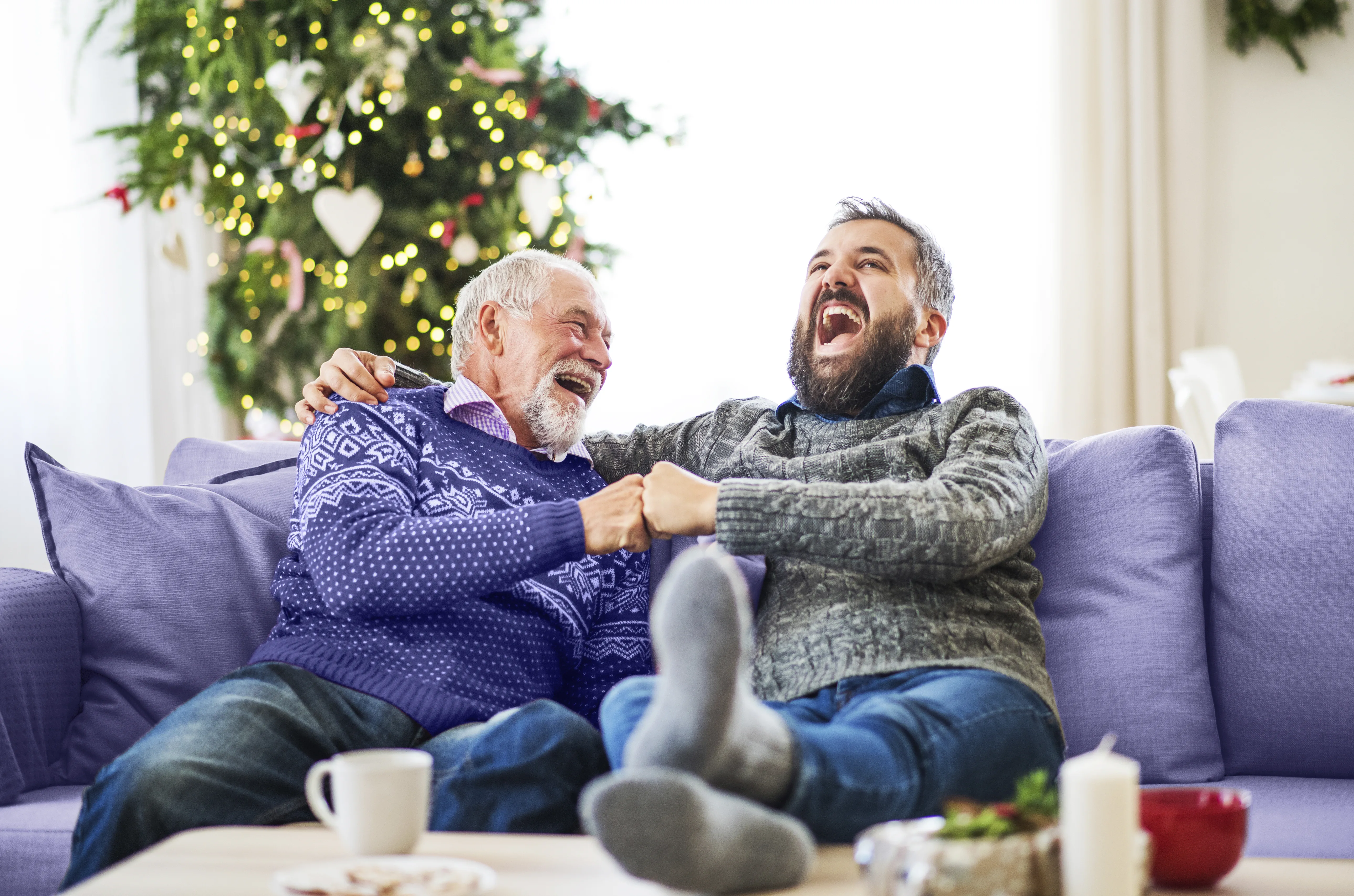 Two men sitting on a sofa laughing